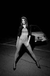 Set activewear donna Elise Daytona a scacchi bianco nero con posa a gambe divaricate e giacca nera in ambiente notturno