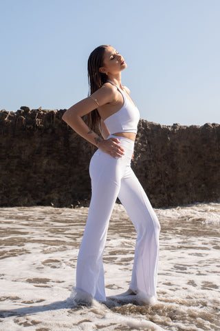 Set activewear donna Sincera bianco con leggings a zampa in posa laterale sulla battigia